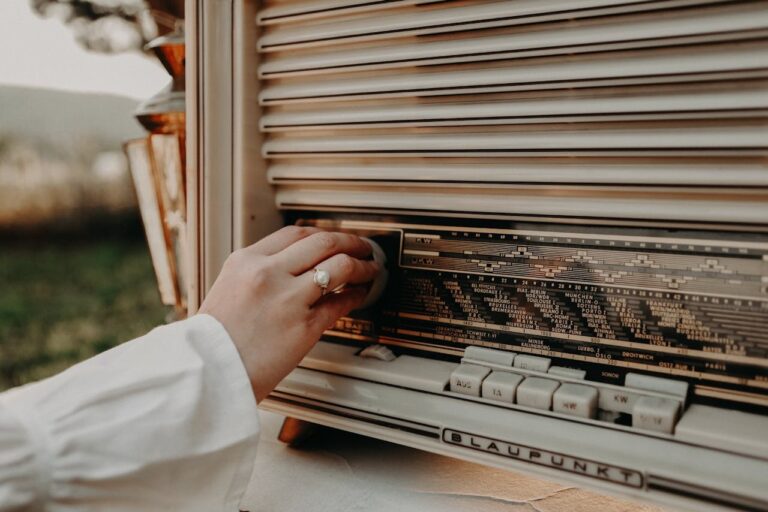 A hand adjusts the dial on a classic vintage Blaupunkt radio outdoors.
