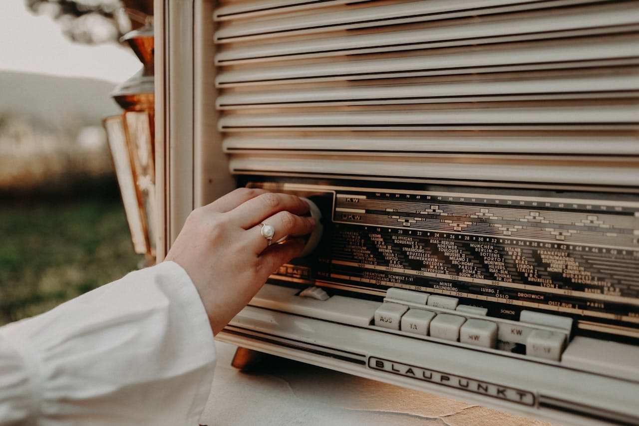 A hand adjusts the dial on a classic vintage Blaupunkt radio outdoors.